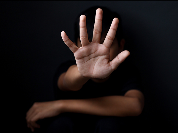 Hand in stop position coming out of darkness over a folded arm.
